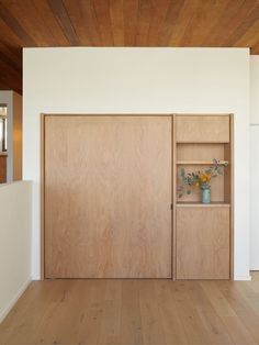 an empty room with wooden doors and shelves on the wall next to a white wall