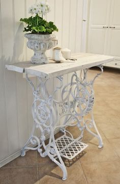 a white table with a potted plant sitting on it's side next to a wall