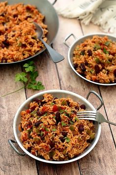 two bowls filled with rice and beans on top of a wooden table next to a fork