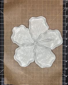 a white flower sitting on top of a piece of paper next to a cutting board