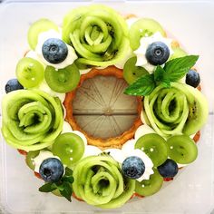 a cake decorated with green and blueberries on top of a plastic container filled with icing