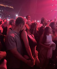 a group of people standing around in front of a crowd at a concert with bright lights