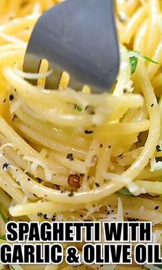 spaghetti with garlic and olive oil is being held up by a spatula over it