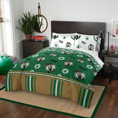 a bed with green and white comforters in a room next to a window, potted plant