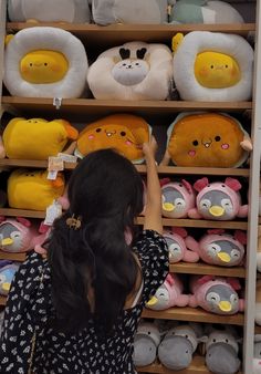 a woman looking at stuffed animals on shelves