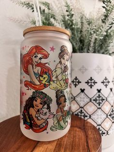 the disney princesses are painted on this glass jar with straws in front of some potted plants