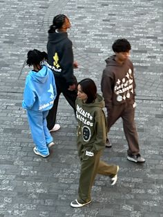 four young people walking down a brick sidewalk