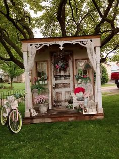 a bicycle is parked in front of a small shed with flowers on the door and windows