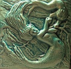 a close up of a green vase with a mermaid on it's face and body