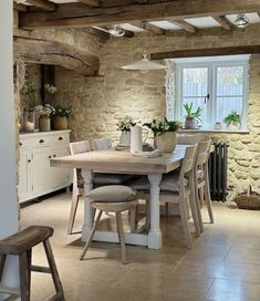 a dining room table with chairs and potted plants