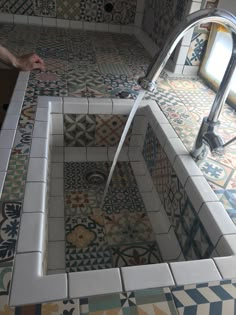 a bathroom with multicolored tiles and a faucet running from the sink