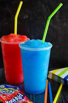 two drinks are sitting next to each other on a table with candy and candies