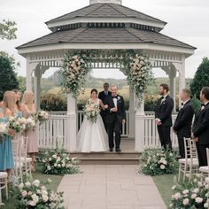 a bride and groom walking down the aisle at their outdoor wedding ceremony in front of a gazebo