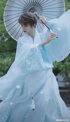 a woman dressed in white holding an umbrella