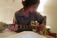 a woman is playing an electric guitar in her bed