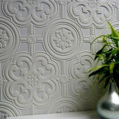 a potted plant sitting on top of a table next to a white wallpaper