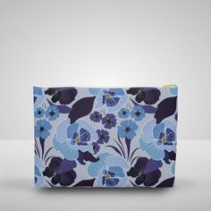 a blue and purple flowered pouch bag on a white surface with a grey background