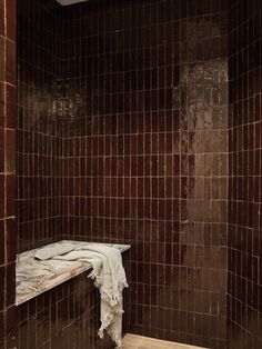 a tiled bathroom with a bench in the corner and tile on the wall behind it