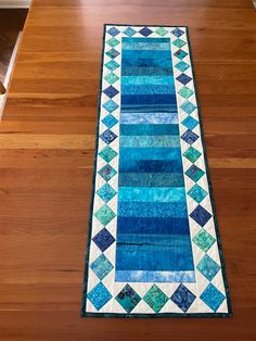 a blue and white table runner on top of a wooden floor