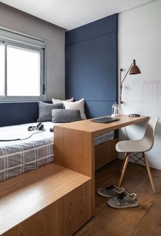 a bed sitting next to a window in a bedroom under a desk with a computer on top of it