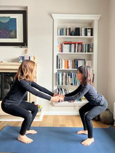 two young women practicing yoga in front of a bookcase