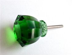 a green glass bead on a white surface with a screwdriver next to it