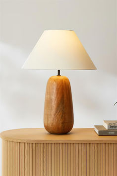 a wooden table with a lamp on top of it next to a book and a plant