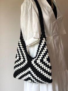 a black and white crocheted bag hanging on a mannequin headdress