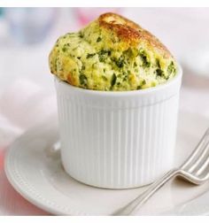 a white plate topped with a muffin on top of a table next to a fork