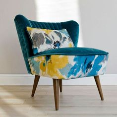 a blue chair with a yellow and blue pillow on it in front of a white wall