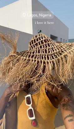 a woman wearing a straw hat and sunglasses on her head, with the caption i love it here