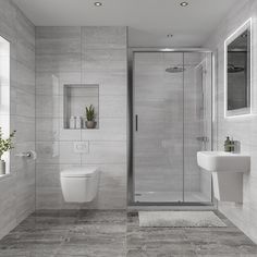 a bathroom with a toilet, sink, and shower stall in grey marbled tile