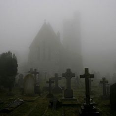 an old church in the fog with tombstones