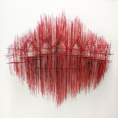 a red sculpture is shown in front of a white wall