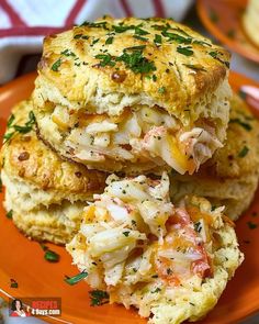 two biscuits stacked on top of each other with cheese and meat in the middle, sitting on an orange plate