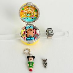 a small compact case with some charms on it and a keychain in the shape of mickey mouse