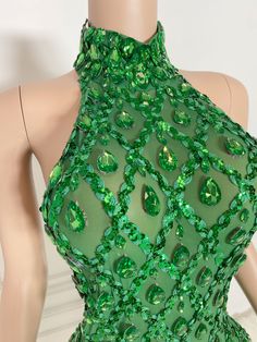 a mannequin wearing a green dress with lots of jewels on it's neck