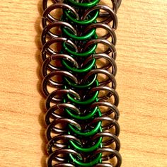 a close up of a metal object on a wooden surface with green and black springs