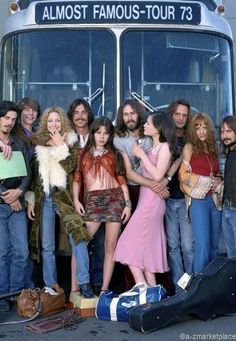 a group of people standing in front of a bus with their arms around each other