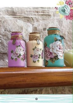 three jars with flowers painted on them are sitting on a shelf in front of a stone wall