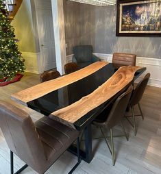 a dining room table with chairs and a large wooden slab on the center piece, in front of a christmas tree