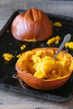 a close up of a bowl of food on a tray next to an orange pumpkin