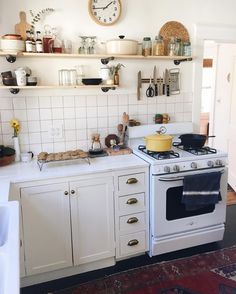 a white stove top oven sitting inside of a kitchen next to a wall mounted clock