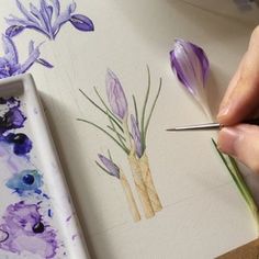 someone is painting flowers with watercolors on paper