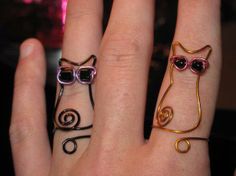 three rings with cats and swirls on them, one is wearing sunglasses the other has a cat's head