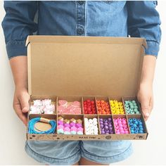 a person is holding a box full of different colored buttons and pins on it's side