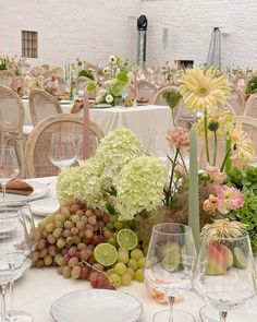 the table is set with many different types of food and wine glasses, including grapes