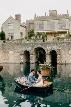 a bride and groom are in a boat on the water near a castle like building