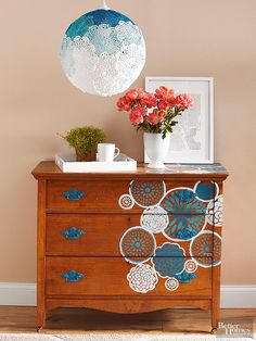 a wooden dresser with flowers on top and an umbrella hanging from the ceiling above it