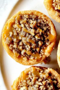 several small pastries on a white plate with walnuts and pecans in the middle